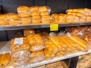 Parker, Colorado, ABD-27 Mayıs 2025 - Plastiğe sarılmış ve bir marketin rafına istiflenmiş ekmek somunlarının yakın çekimi. Fırınlanmış yiyecekler yumuşak rulo ve kolay ayarlanmış sandviç somunlarını içeriyor.