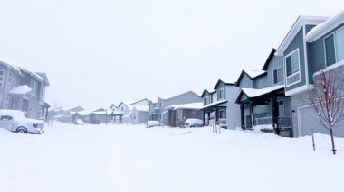 Castle Rock, Colorado, ABD-14 Mart 2024-Ağır çekim sahnesi, karla kaplanmış bir cadde boyunca uzanan ve kış boyunca uzanan berrak bir patikayla noktalanmış evlerle banliyö sükunetini tasvir ediyor.