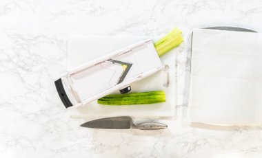 A cucumber is sliced thinly using a mandoline slicer to prepare for Mini Cucumber Sandwiches. Perfect for how-to recipes, food blogs, or kitchen technique tutorials.