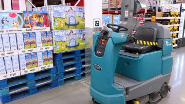 Castle Rock, CO, ABD-11 Kasım 2025 - Büyük bir ticari zemin temizleme makinesi perakende ürün paletlerinin yanına park edilmiştir. Parlak ışıklandırılmış depo koridorunda...