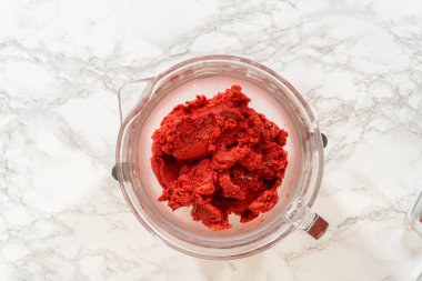 Klasik Kızıl Zencefilli Ekmek 'in canlı kırmızı hamuru tamamen karıştırılmış bir cam karıştırma kabında, derin rengini ve pürüzsüz dokusunu sergiliyor, pişirmeden önce soğutulmaya hazır..