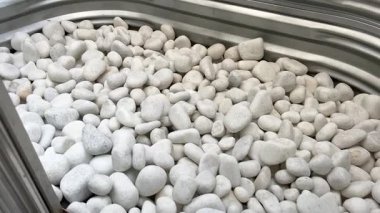 Eğri büğrü bir çelik pencerenin dibinde duran pürüzsüz beyaz nehir taşlarının ayrıntılı görüntüsü. Dış ev güvenliği ve tasarım geliştirmeleri için harika bir örnektir..