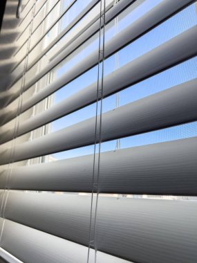 Beyaz yatay pencereler içeriden görünüyor, çoğunlukla kapalı, en az gün ışığının geçmesine olanak sağlıyor. Temiz hatlar modern ve minimal bir pencere tedavisi sağlar..