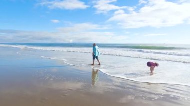 California 'da bir baba ve kızı, El Capitan Eyalet Plajı' nın ıssız kumları boyunca sakin bir kış yürüyüşünü paylaşıyor..