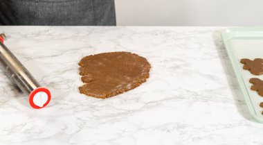 Erkek şeklinde zencefilli hamurun parşömen astarlı fırın tepsisine düzgünce yerleştirilmiş fırın için hazır olması..