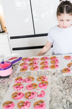 Odaklanmış bir dikkatle, bu filizlenen aşçılık sanatçısı krakerleri erimiş çikolataya batırarak iyi aydınlatılmış bir ev mutfağının sıcaklığında tatlı tatlar yaratıyor..
