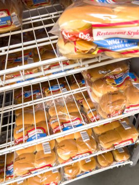 Parker, Colorado, ABD-20 Haziran 2025 - Bir market rafında paketlenmiş sosisli çörekler ve depo tarzı bir dükkanda çeşitli somunlar sergileniyor. Ürünler türlerine göre düzenlenir ve beyaza göre düzenlenir