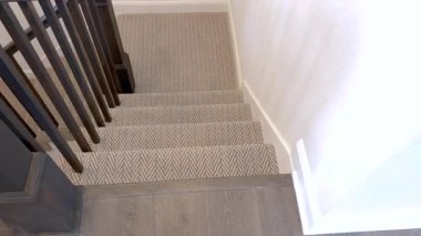 Yumuşak ringa balığı desenli halı koşucusu ve ahşap tırabzanlarla merdivenlerin üstünden. Parlak ışıklandırma temiz çizgileri vurgular.