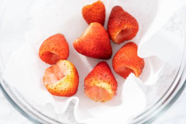 Taze yıkanmış ve kurutulmuş çilekler kağıt havluyla kaplı cam bir kasede dikkatlice düzenlenir. Atıştırmaya ya da daha fazla kullanılmaya hazır hale getirilir..