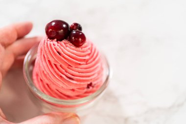 Cam bir kavanoza konmuş ve üzerinde taze yaban mersini olan canlı bir kızılcık kreması. Bu krema, tart kreması kurabiyeler, pastalar ve bayram tatlıları için mükemmel..