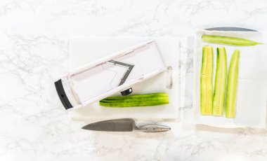 Taze dilimlenmiş salatalık, Mini salatalık sandviçi tarifinin bir parçası olarak nemlendirilecek kağıt havluların üzerine serilmiş. Yemek hazırlamak için ideal çizimler ya da sağlıklı atıştırma dersleri için..