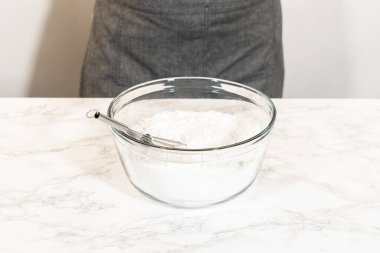 İçi pudra şekerli cam bir karıştırma kabına yerleştirilmiş çırpı, Sade Beyaz Kraliyet Buzlanma hazırlığı için hazır..