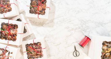 Süslü zencefilli kurabiyelerle dolu, kırmızı kurdeleyle bağlanmış birden fazla beyaz hediye kutusunun bulunduğu bir apartman dairesi. Bayram hediyeleri arasında klasik zencefilli çörek adamlar, eldivenler ve yıldızlar yer alıyor.