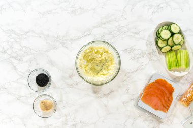 Krem peynir, el bilgisayarı karıştırıcısı kullanılarak cam bir kaseye karıştırılıyor. Somon ruloları için tabanı hazırlıyorlar..