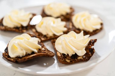 Üstünde nefis çırpılmış krem peynirle çıtır çıtır gurme kraker manzarası. Bakış açısı dokuyu ve tasarımı vurgular, bu aperatifleri üst sınıf için mükemmel yapar.