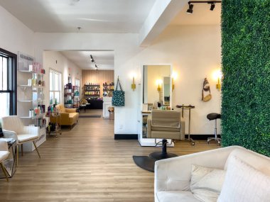 Parker, Colorado, ABD-3 Temmuz 2025 - Parlak ve açık bir kuaför salonu manzarası, doğal ışık, yeşil aksan duvarı ve ahşap zemin. Çoklu tasarım istasyonları ve raflar