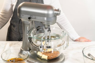 Karıştırma kabında Amber Zencefilli Kurabiye Hamuru 'nun malzemelerinin bulunduğu bir tezgahın yan görüntüsü, mermer tezgahın üzerine yerleştirilmiş, yakınlardaki ıslak malzemelerle dolu ayrı bir kase,