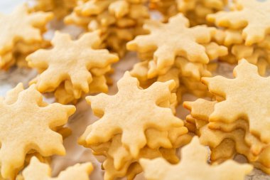 Altın rengi, taze pişmiş şekerli kurabiyeler. Şenlikli kar taneleri şeklinde. Düz bir yüzeyde soğuyor..