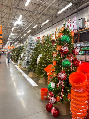 Süpürge, CO, USA-1 Kasım 2025 - Süs ve ışıklarla süslenmiş yapay Noel ağaçları bir mağaza koridoru boyunca sergilenmektedir. Parlak turuncu kovalar ve şenlikli dekorasyonlar neşe saçar.