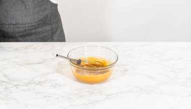 Mermer tezgahın üzerindeki bir cam karıştırma kabında pekmez, vanilya özü ve baharatlı zencefilli kurabiye kurabiyesi için çırpılmaya hazır bir yumurta bulunur. Bu karışım zengin, derin yaratmaya yardımcı olur.