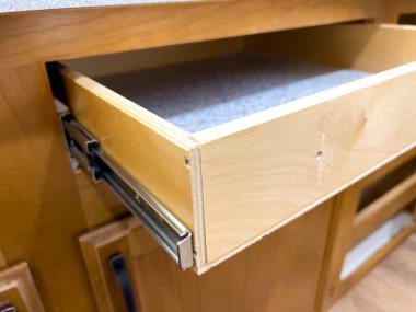 Metal demiryolu sisteminde bir mutfak çekmecesi dışa doğru genişletilir, iç ahşap yüzeyleri ve destekleyici donanımı gösterir. İçerideki sıcak aydınlatma kabinenin altını çiziyor.