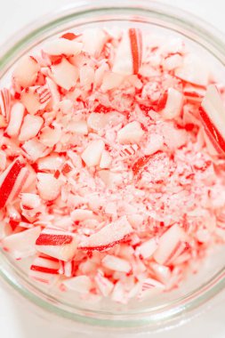 Ezilmiş şeker kamışlarıyla dolu cam bir kavanoz, mermer tezgahta sergileniyor, canlı kırmızı ve beyaz çizgileri tatil tatlısı dekorasyonu ve pişirme için sergileniyor..