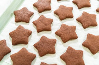 Çikolata yıldızlı kurabiyelerin parşömen kağıdının arka planında yakın plan görüntüsü..