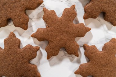 Mermer bir yüzeyde kar tanesi şeklinde üç çikolatalı zencefilli kurabiye gruplandırılmış düzenleme. Üniforma tasarımları ve şenlikli cazibeleri gözler önüne seriliyor..