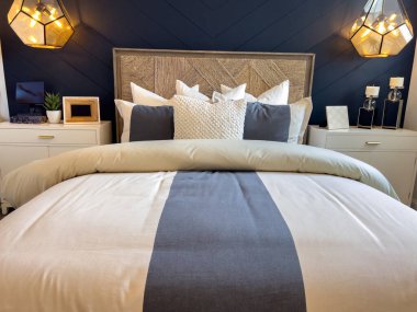 Kolye ışıklarıyla çerçevelenmiş yatağın merkezi odak noktası olan modern yatak odası. Mavi uzun metrajlı duvar ve nötr yatak sakin ve şık bir iç mekan oluşturur..