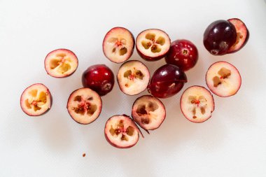 İkiye bölünmüş taze kızılcıklar, canlı kırmızı derileri, karmaşık iç kısımları ve küçük tohumları sergiliyor. Sulu doku ve doğal detaylar bu resmi resmetmek için ideal hale getiriyor.