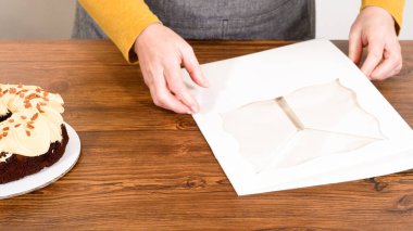 Tuzlu karamel şekerlemeleri ve zencefilli ekmek parçacıklarıyla süslenmiş zencefilli keki dikkatlice hediye etmek için açık pencereli beyaz bir kağıt bohça kek kutusuna yerleştiriyorum..