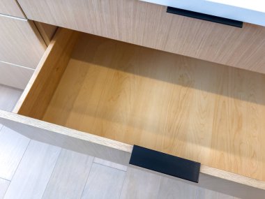 Ahşap mutfak çekmecesi kısmen siyah saplı ve modern tasarımı temiz. Ayrıntılar konut işlevselliğini ve asgari dekorasyonu vurguluyor.