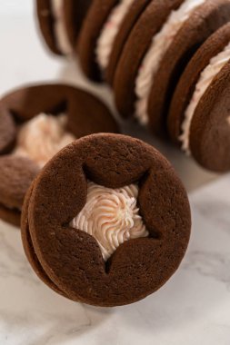 Tek bir çikolatalı sandviç, yıldız kesiminden geçen bir krema merkezini gösteriyor. En düşük arkaplan ve yumuşak ışıklandırma şekli ve rengi vurguluyor.