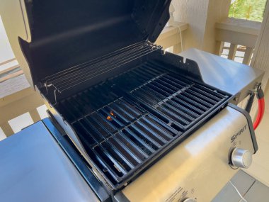 Parker, Colorado, ABD-27 Nisan 2025 - Weber Spirit gaz ızgarasının içi kapağı açık gösterilir. Izgaralar pırıl pırıl ve ızgara bir konut avlusunda kurulmuş..