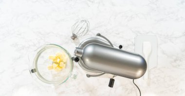 Görüntü tereyağı küplerini karıştırma kabına koyuyor. Limonlu kurabiye için diğer malzemelerle karıştırılmaya hazır..