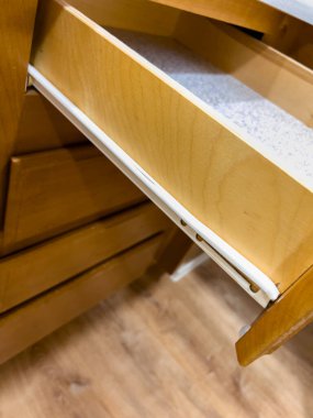 Ahşap bir mutfak çekmecesi metal slaytlarda dışa doğru genişletilir, bitmemiş ahşap iç ve tezgah kenarlarını ortaya çıkarır. Çevredeki dolaplar aydınlık bir mutfak ortamı yaratıyor.