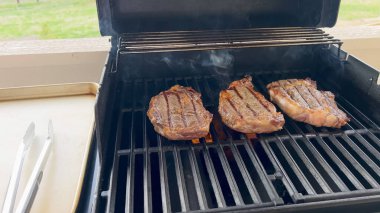 Izgara biftekler gözle görülür yanık izleri olan sıcak bir barbeküde dinleniyor. Izgara verandada ya da güvertede..