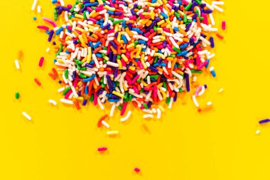 Etrafı şekerlerle çevrili renkli gökkuşağı parçacıklarıyla dolu metal ölçü kabı. Festival tasarımları, tatlı temalı grafikler ve şekerleme markalaşması için kullanışlı.