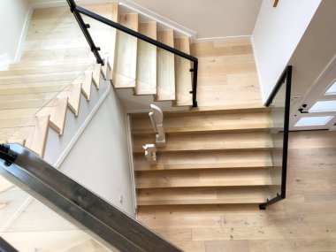 Parker, Colorado, ABD-26 Ağustos 2025 - Evin üst katına uzanan siyah parmaklıklı modern bir ahşap merdiven. Merdivenler beyaz duvarlar ve ahşap döşemeler ile çevrili.