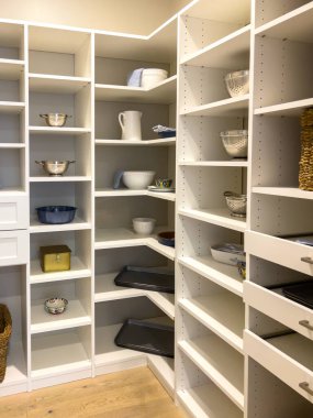 Sepetler, kavanozlar ve katlanmış çarşaflarla dolu beyaz raf üniteleri olan düzenli kiler. Yerleşim düzeni ve işlevselliği yumuşak doğal ışıklandırmayla vurguluyor. Tarafsız tonlar bir...