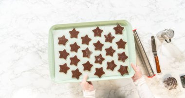 Yeni kesilmiş, çikolatalı zencefilli kurabiyelerle dolu, fırınlanmaya hazır bir yemek tepsisi..