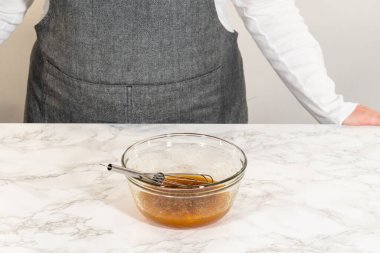 Mermer tezgahın üzerine yerleştirilmiş yumurta ve akçaağaç pekmezli küçük bir cam kasenin önü. Çikolata, zencefilli kurabiye ve çörek karışımına eklenmeye hazır..