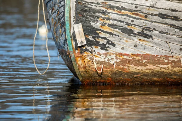 Starý dřevěný rybářský člun ve vodě, potřebuje malovat — Stock fotografie