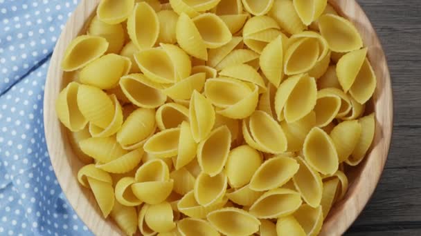 Pasta italiana sotto forma di conchiglie, fondo in legno. macro — Video Stock