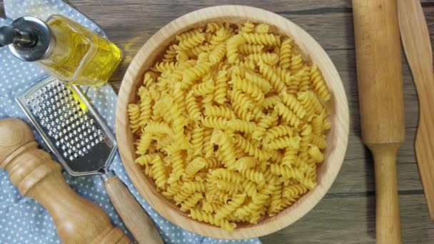 La pasta Fusilli seca sobre la mesa gira lentamente. Sobre fondo de madera. Vista superior. — Vídeos de Stock