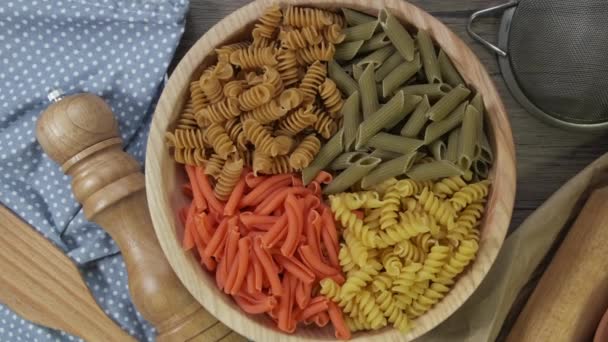 Pasta multicolor girando en cámara lenta vista superior. Rotación de pasta espiral coloreada 4k. montón de pasta sin cocer. Comida italiana de cerca. Delicioso fusilli italiano. pasta tricolor. antecedentes alimentarios. — Vídeo de stock