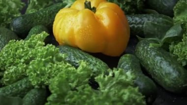 Taze sebze, sarı dolmalık biber, salatalık ve siyah arka planda salata..