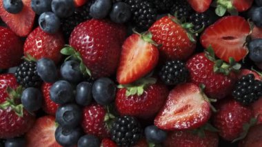 Kara arka planda yabani orman meyveleri, çilek, yabanmersini ve böğürtlen koleksiyonu.