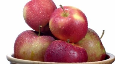 Tahta bir tabakta beyaz bir tabakta kırmızı ve sarı elmalar döner. 4K