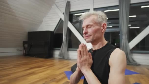 Hombre maduro entre el grupo haciendo ejercicios de yoga. — Vídeos de Stock